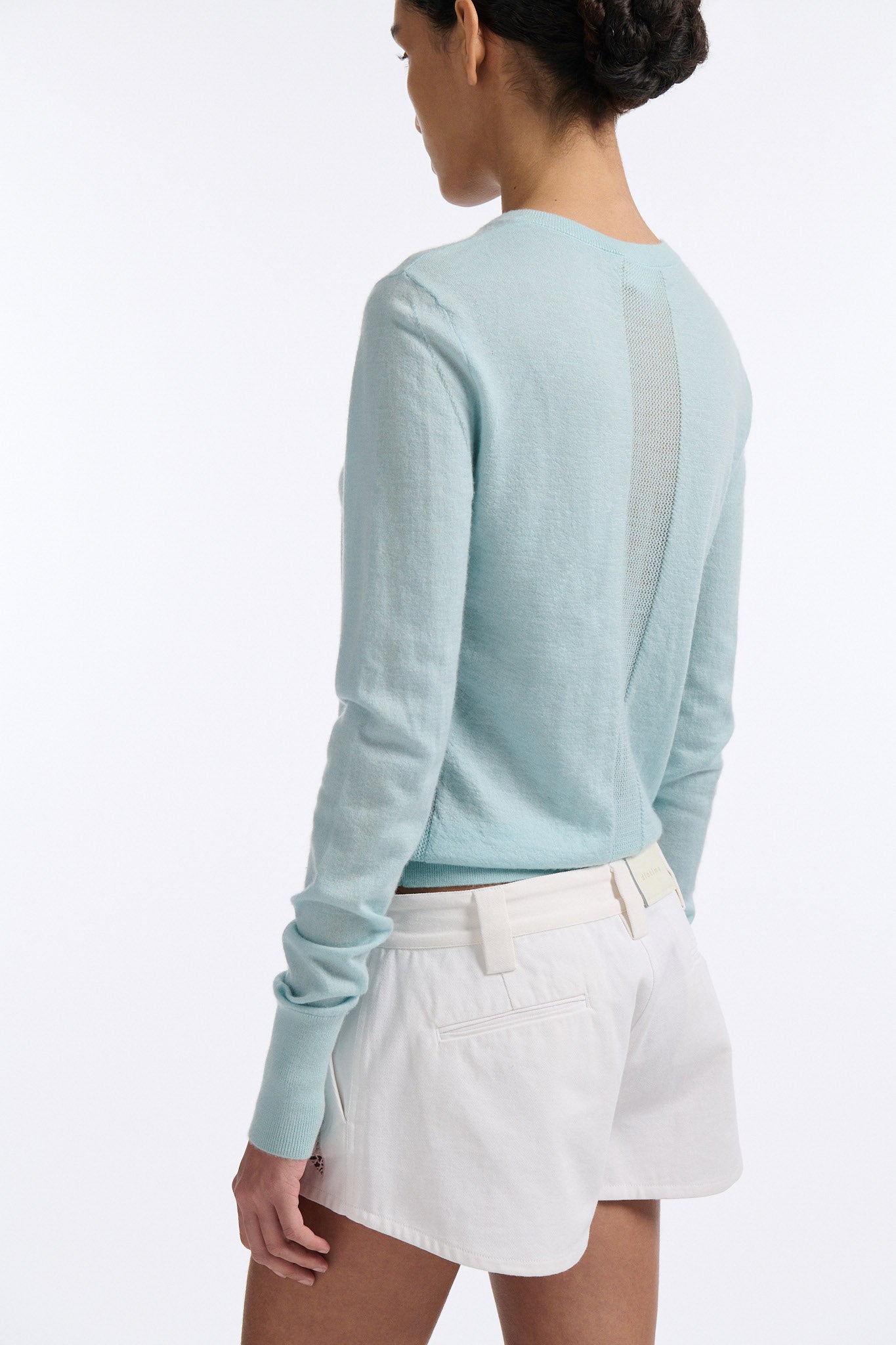 Female model with slicked back black hair in a bun wears