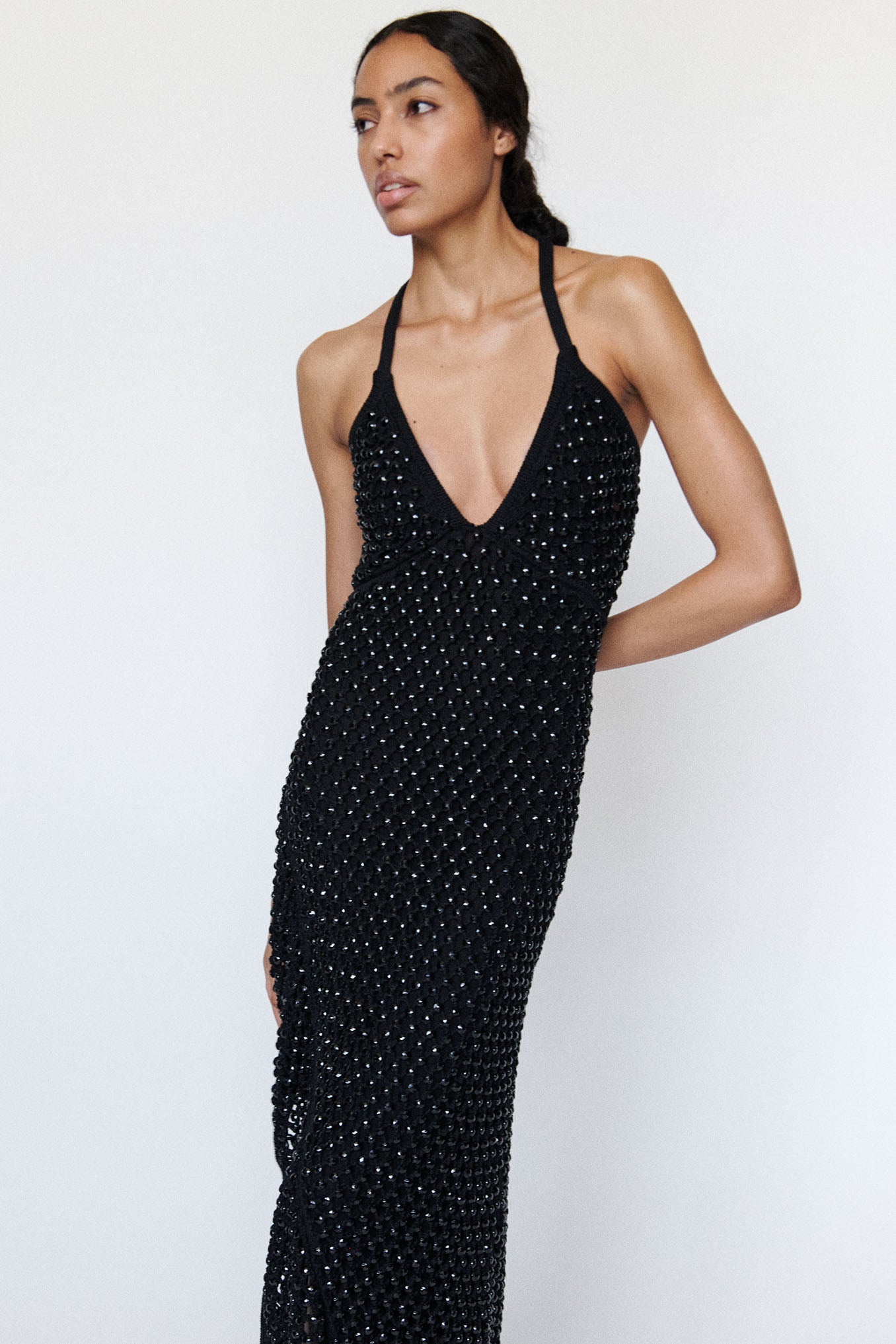 Model wearing black halter top knit dress on a white background. Dress is fully lined mesh with chunky crystals sewn throughout.