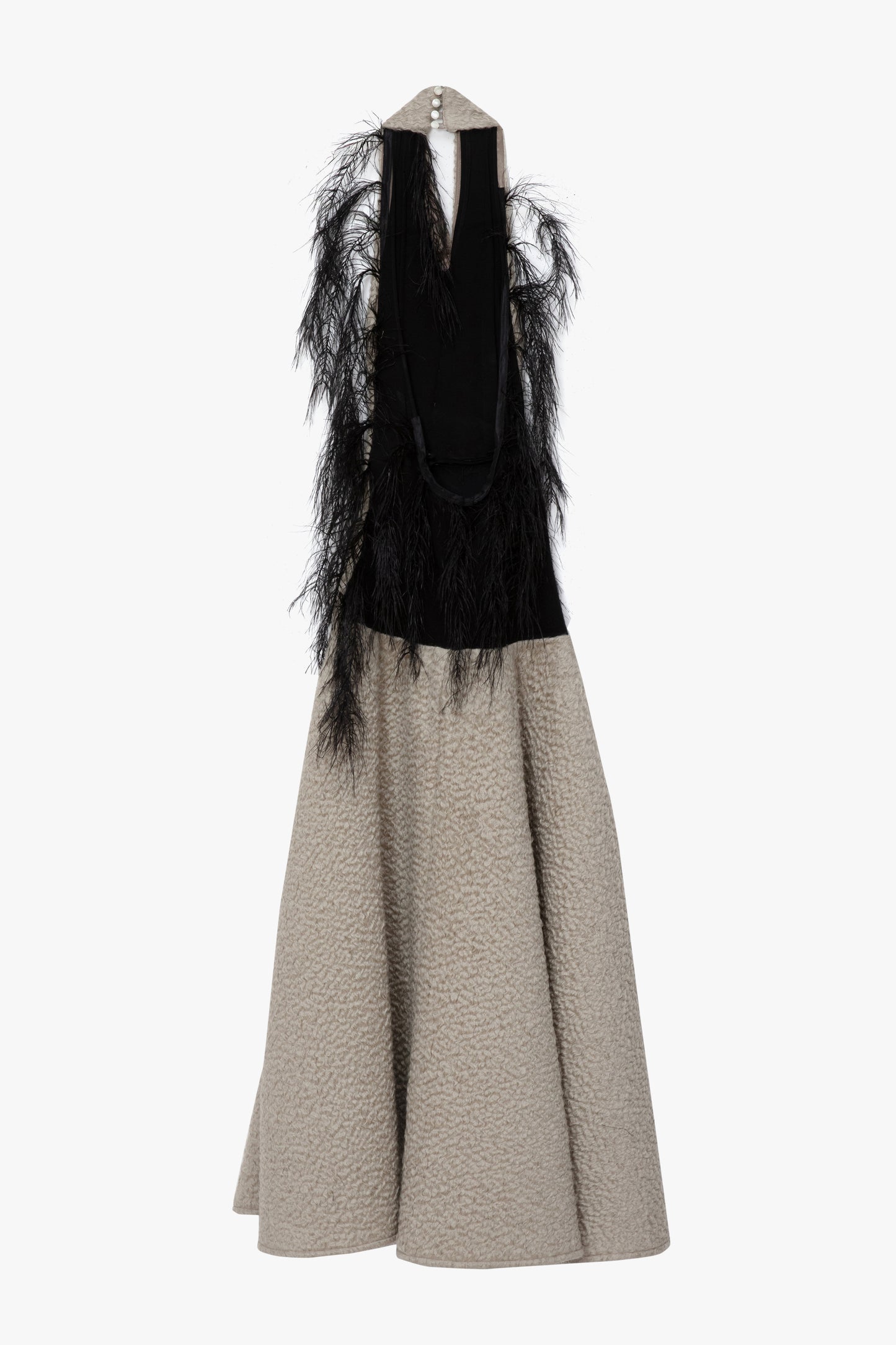 A flat image of the back of a textured parchment halterneck,maxi dress with a wide collar, a black feathered detail. Photographed against a white background.