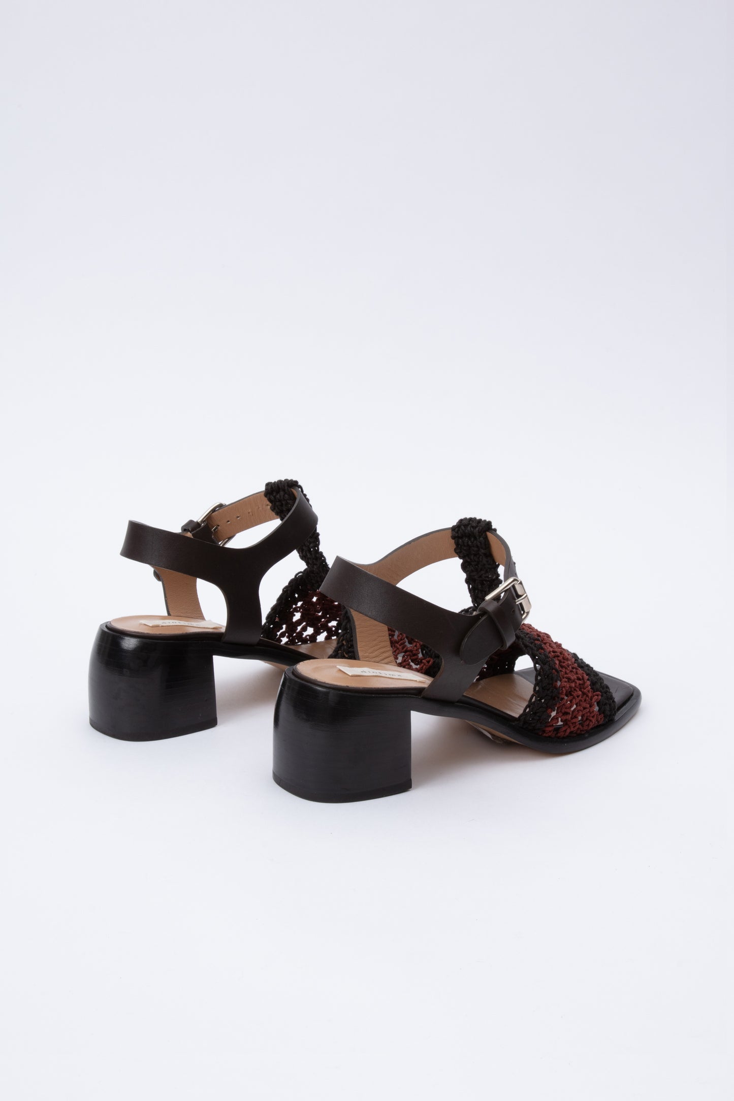 Open toe sandals with black leather base and ankle straps. The block heel is slightly rounded and thick. Connected to the ankle strap is a toe strap made from hand-knit crochet in black and maroon.