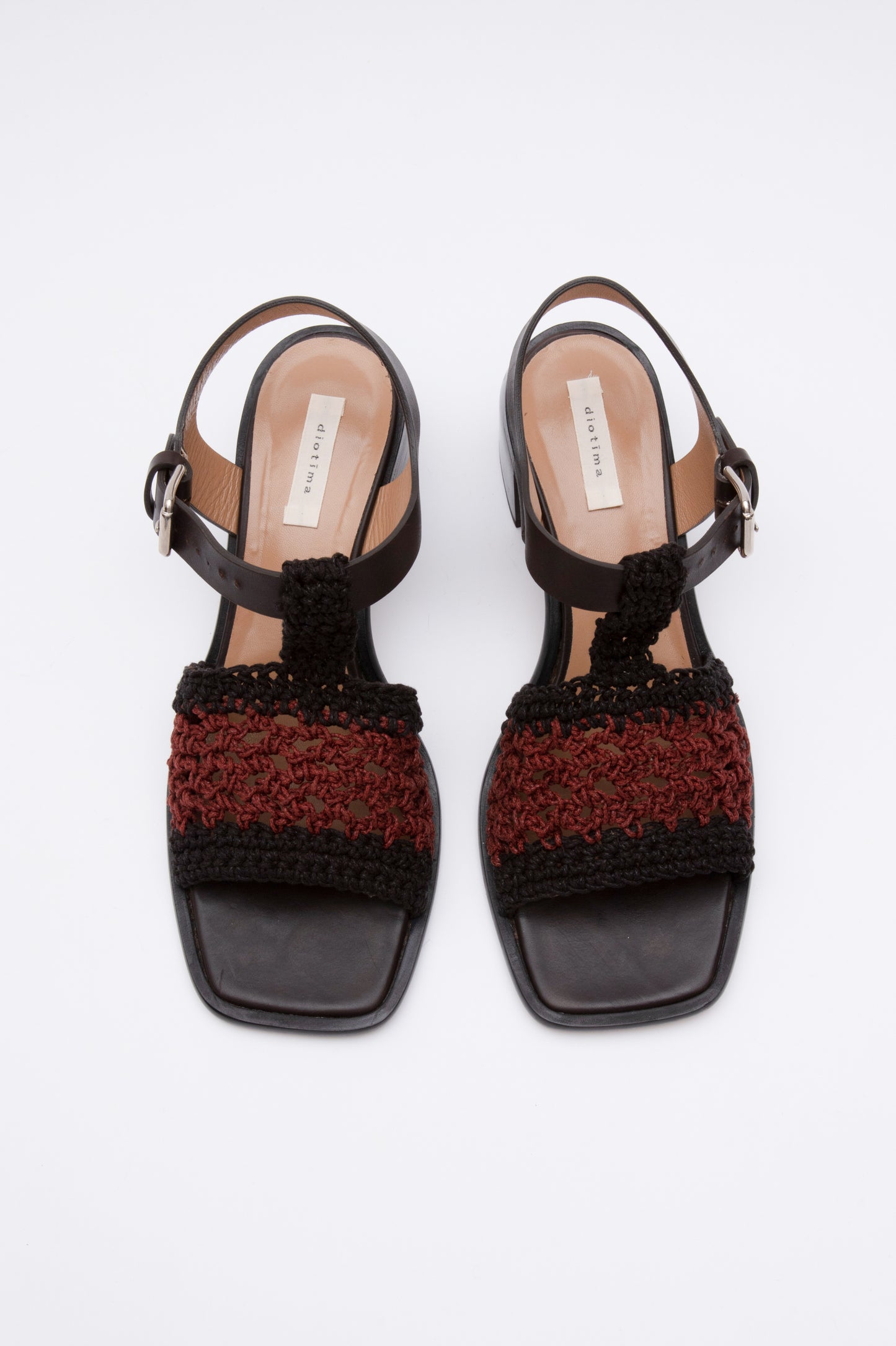 Open toe sandals with black leather base and ankle straps. The block heel is slightly rounded and thick. Connected to the ankle strap is a toe strap made from hand-knit crochet in black and maroon.