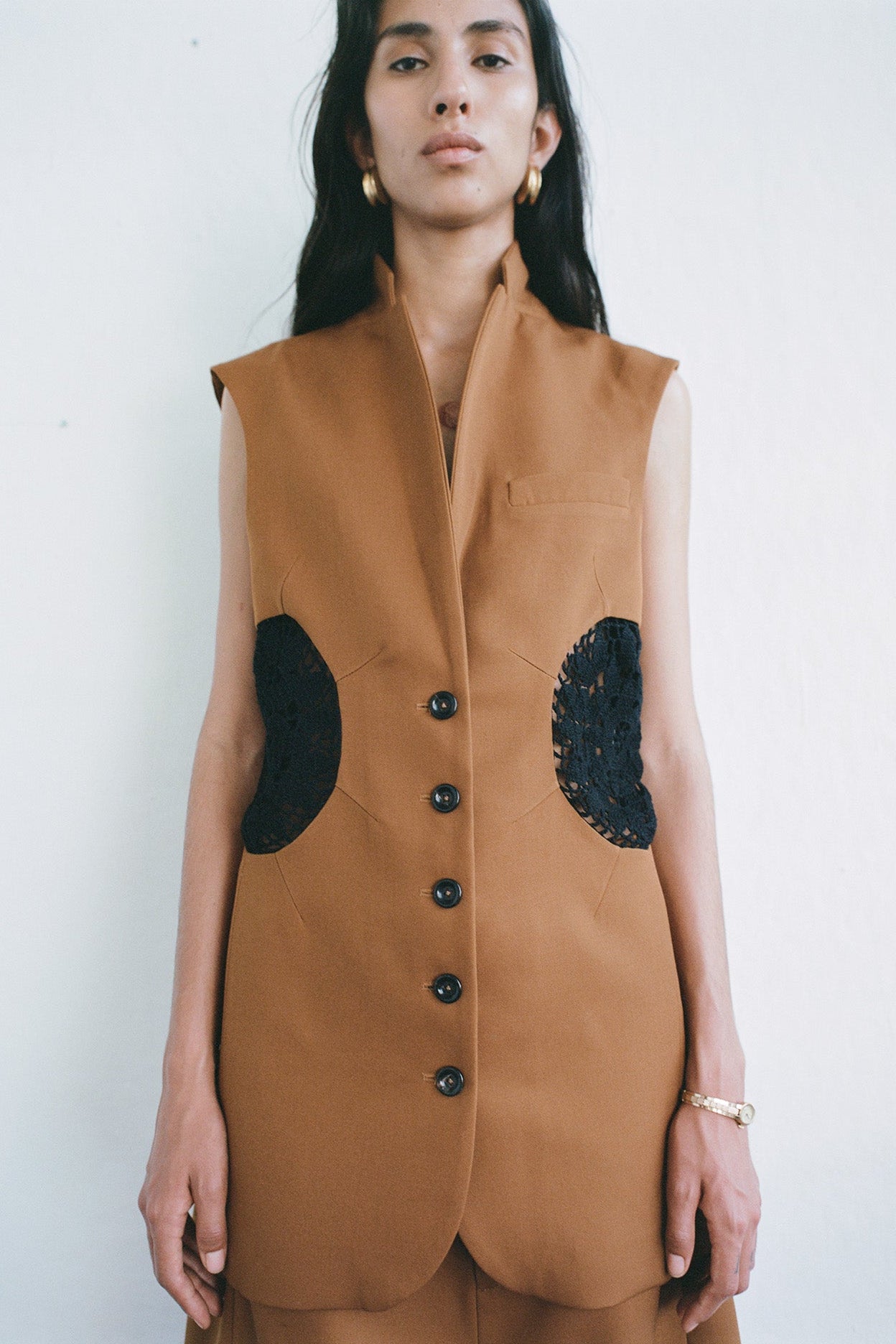 Model wearing a brown vest with black accents photographed on a white background