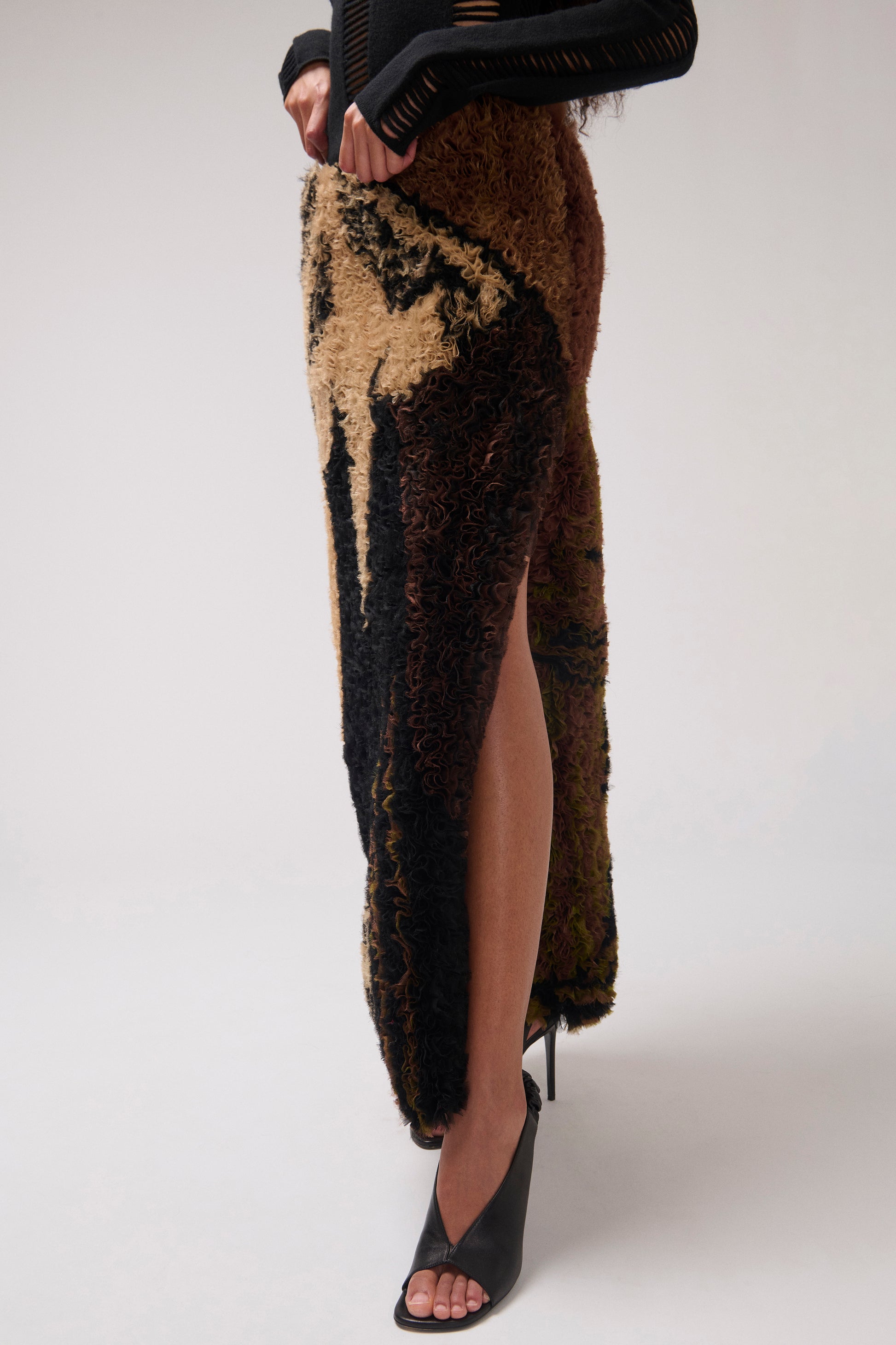 Close up of a model wearing ruffled organza striaght skirt with a dark brown and black abstract pattern, shown. Model is wearing black leather sandals.