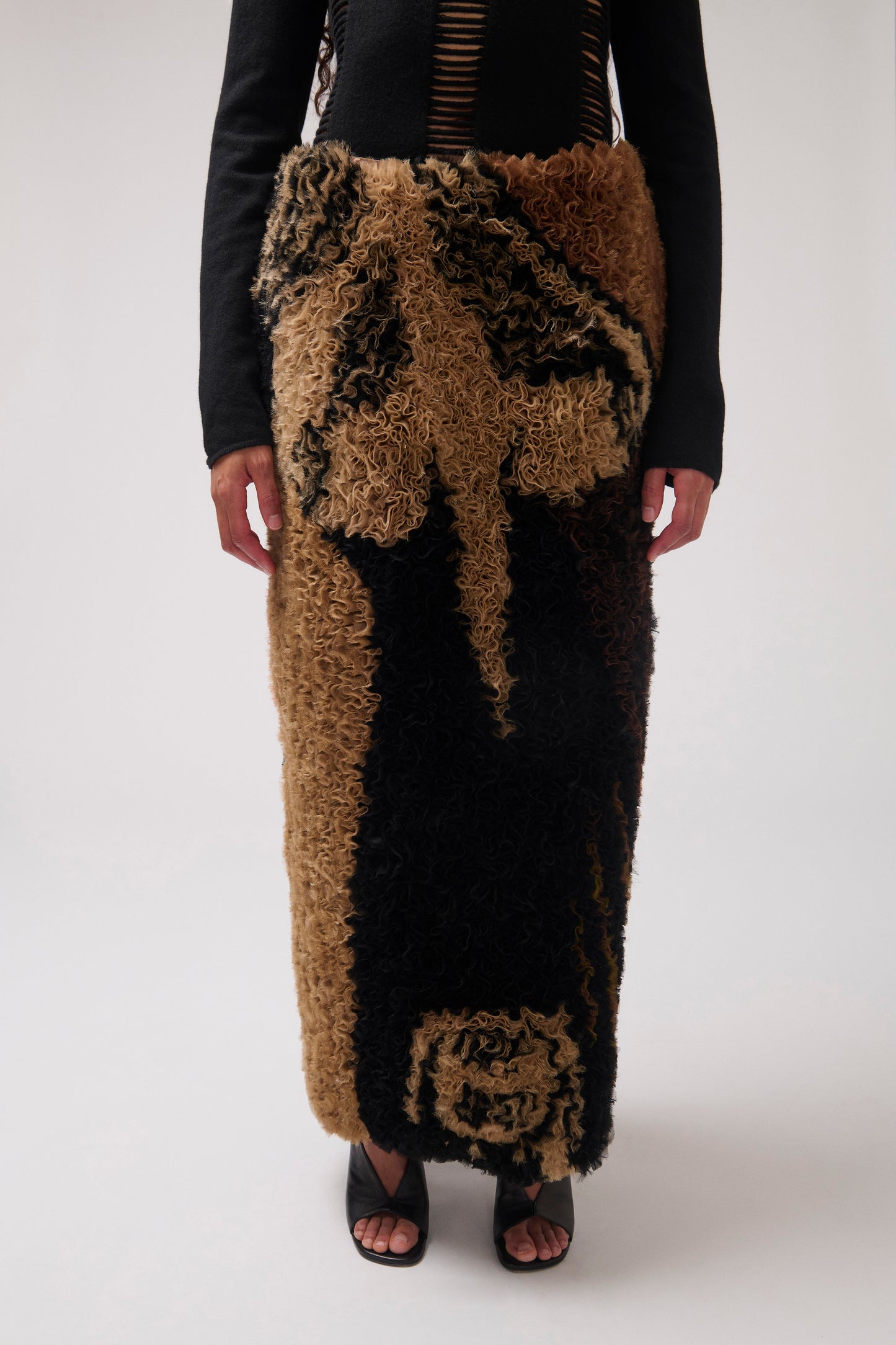 A cropped image of model wearing ruffled organza striaght skirt with a dark brown and black abstract pattern, shown flat against a solid white background.