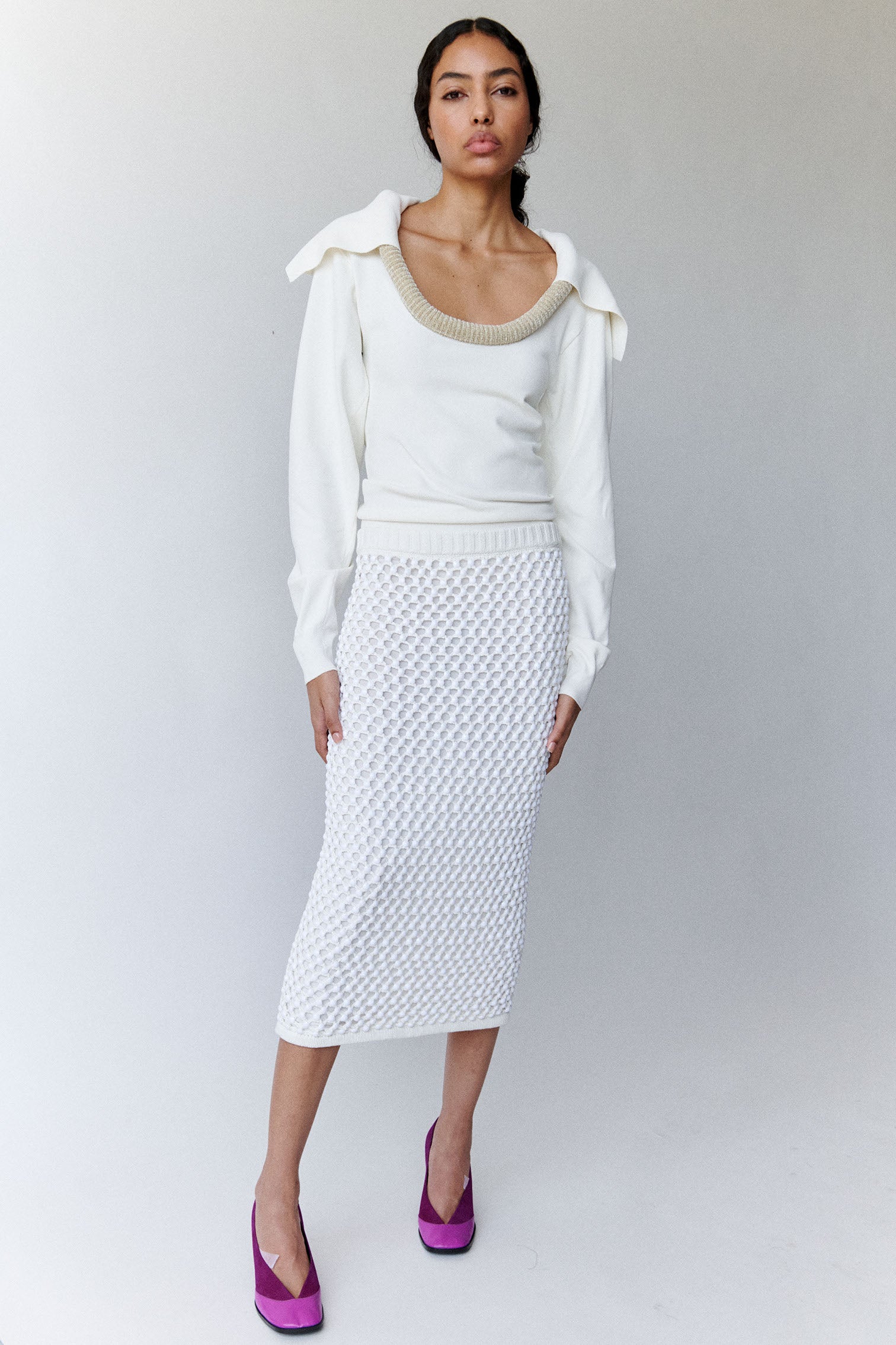 Model wears white sweater with sculptural piping and white crystal embellished straight skirt with magenta pumps. 
