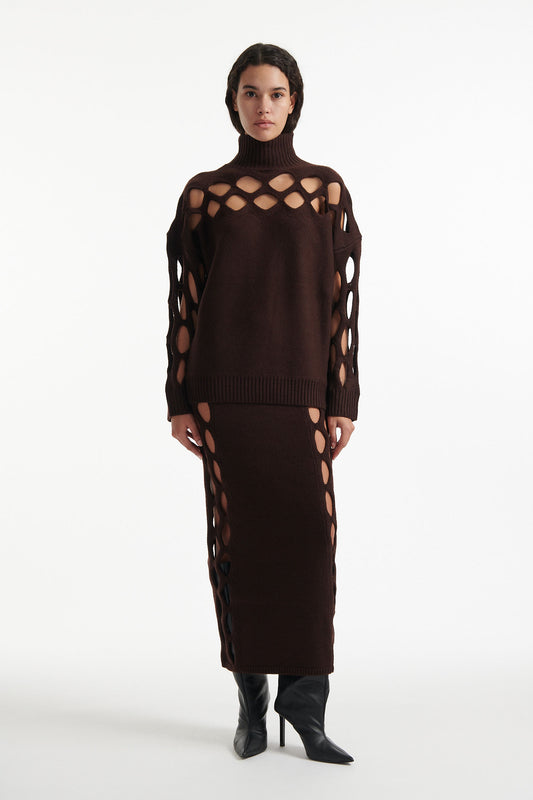 Female model wears open-knit brown long sleeve turtleneck and open-knit brown skirt with black high heels on white background. 