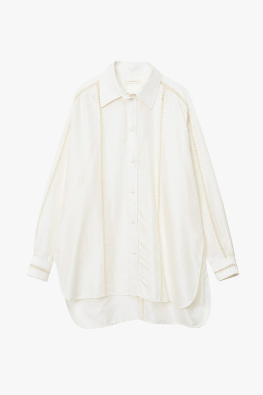A long-sleeve button-up shirt in a warm off-white or cream color, featuring a pointed collar and vertical stitching details.