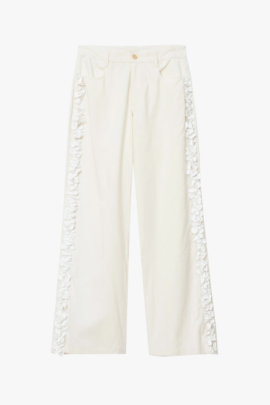 White pants with hand finished details on both legs on a white background