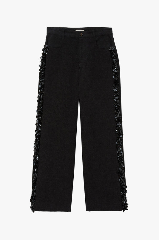 Black denim pants with black flat paillette embellishments along either leg photographed on a white background. 