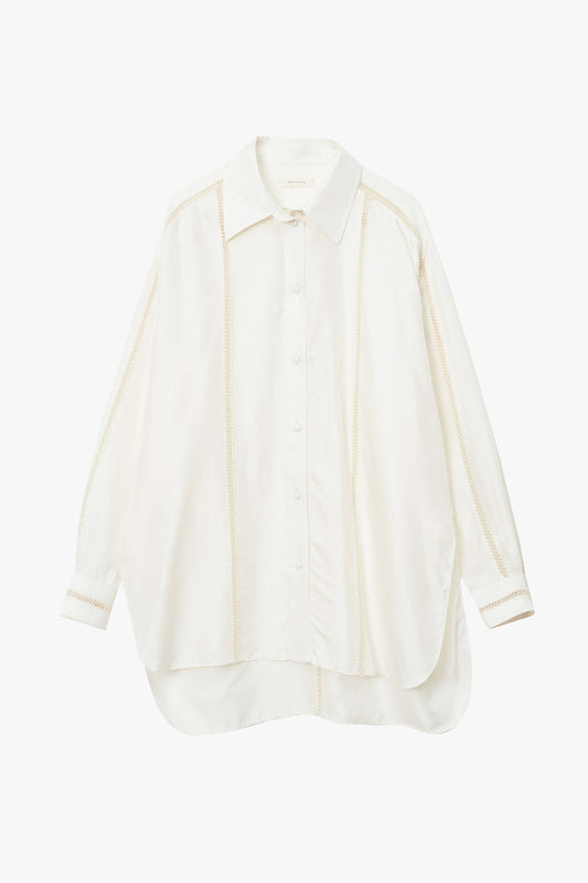 Off-white silk shirt with stripes of beige hand stitched detailing along sleeves, down the chest, and in a T along the back. Photographed on a white background.