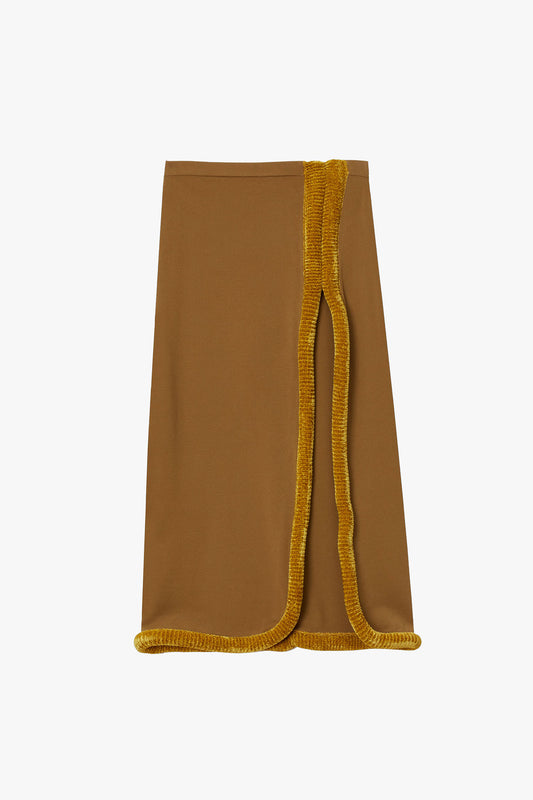 Warm brown high-slit flat knit straight skirt with mustard yellow sculptural tubing at hem and slit photographed on a white background. 