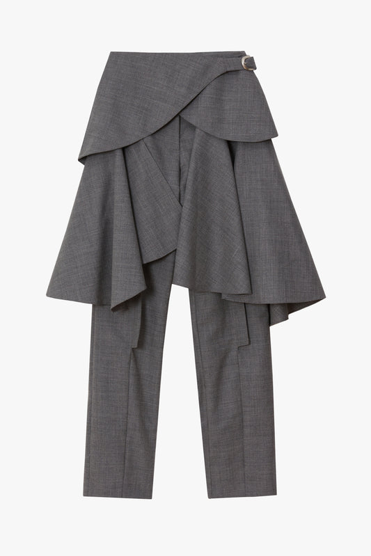 A pair of women's gray plaid trousers featuring a dramatic, asymmetrical layered wrap skirt overlay with a small silver buckle detail at the waist, shown against a plain white background.