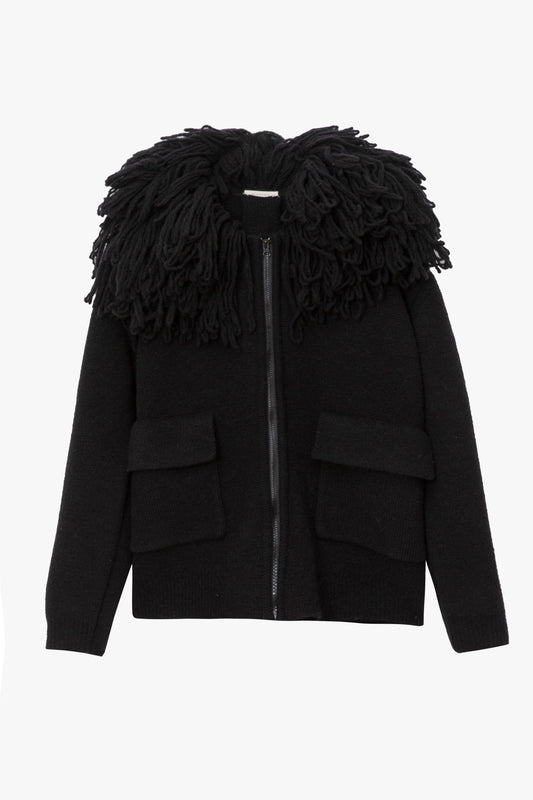 A black wool jacket with an oversized fringe collar and large front patch pockets. The background is a flat white plane.