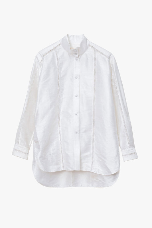 A white long-sleeve button-up shirt with a high-low hem and decorative handl-stitched embroidery, shown against a plain light gray background.