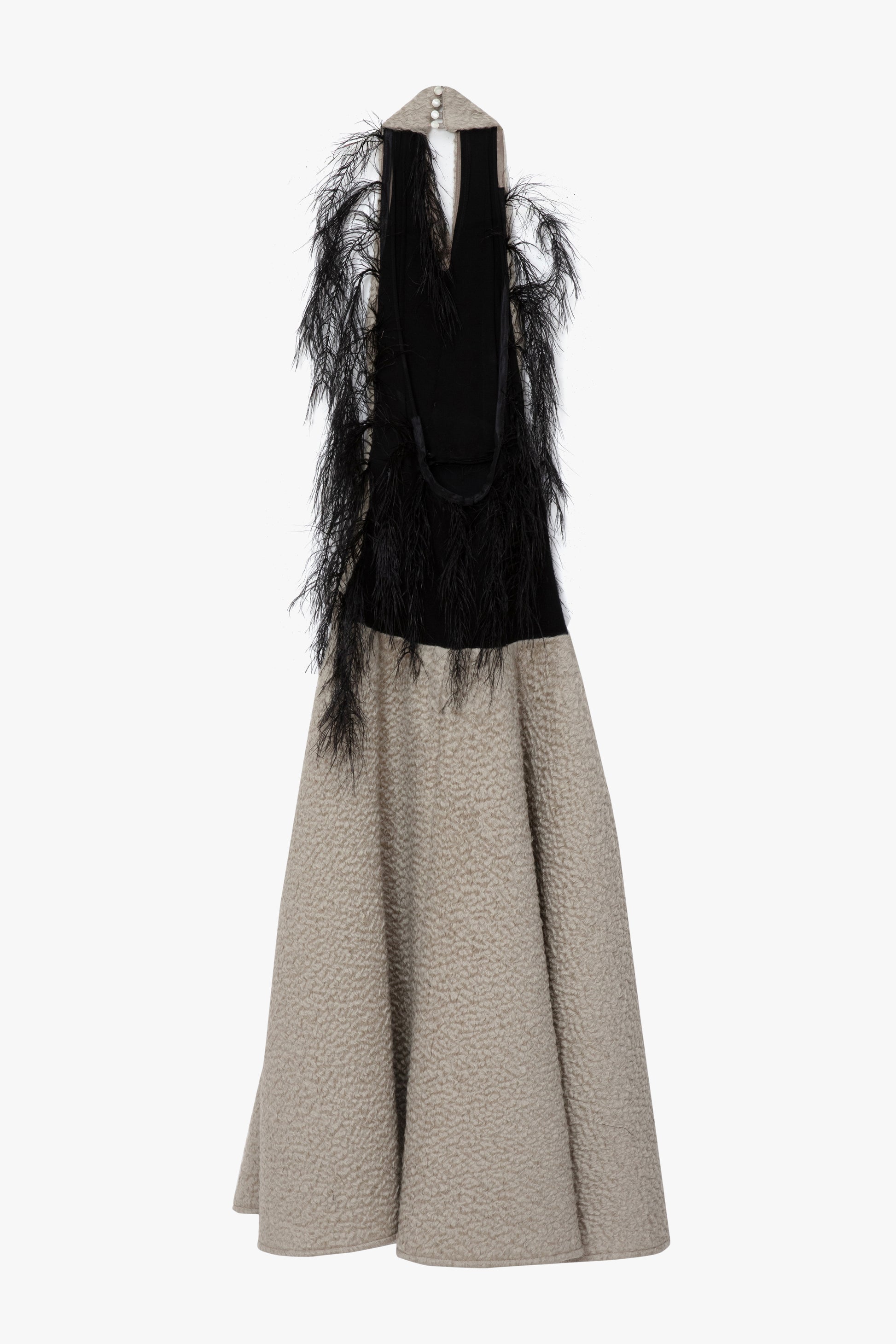 A flat image of the back of a textured parchment  halterneck,maxi dress with a wide collar, a black feathered detail. Photographed against a white background.