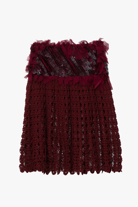 A deep burgundy crochet knit skirt, a ruffled silk waistband, and black ring sequin embroidery.