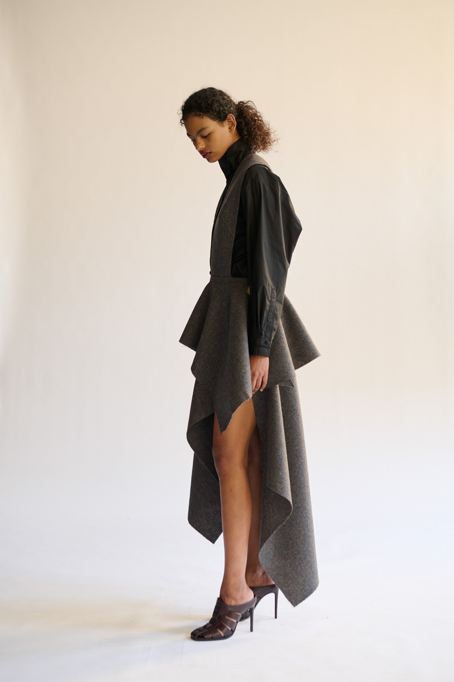 Model wearing a long, dark gray dress with a high-low hem against a white background
