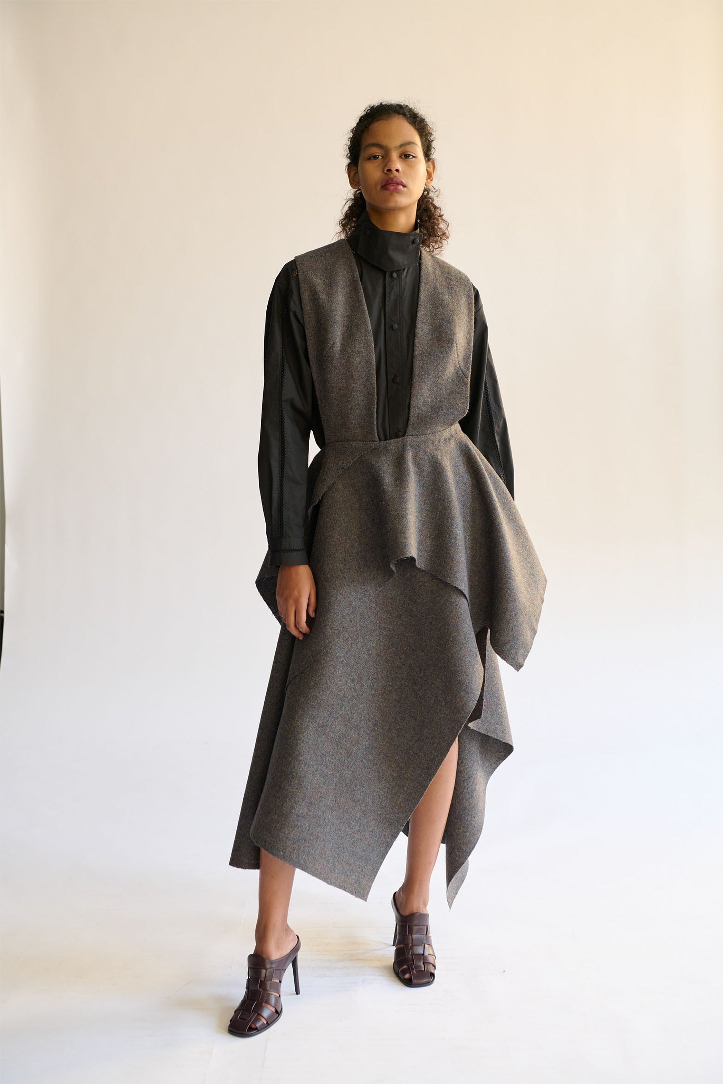 Model wearing a gray outfit with a black button down shirt photographed on a white background 