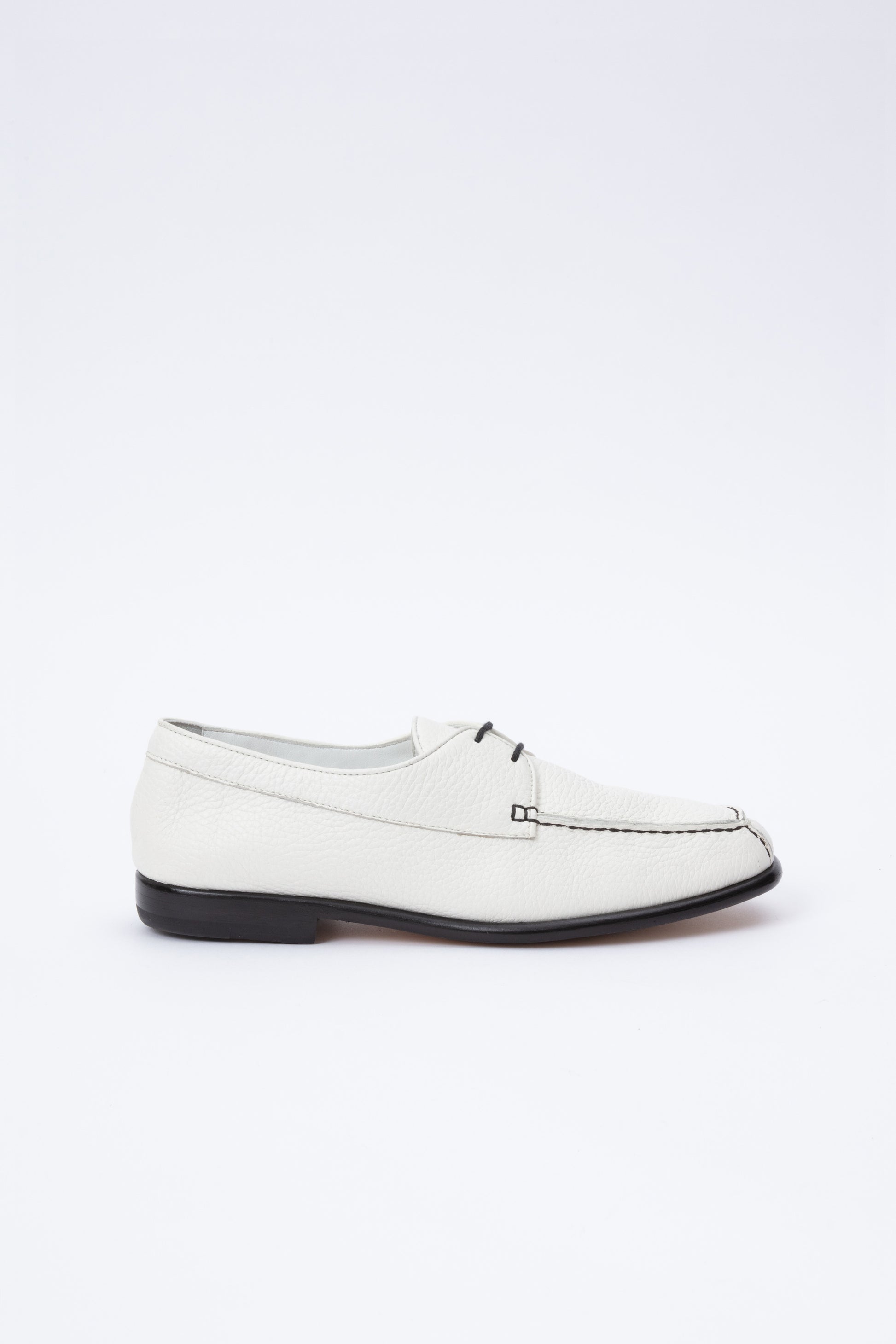 White pebbled leather moccasins with short 1 inch heel and black stitching. Back panel ties at front over short tongue and comes to a squared off point at the toe.