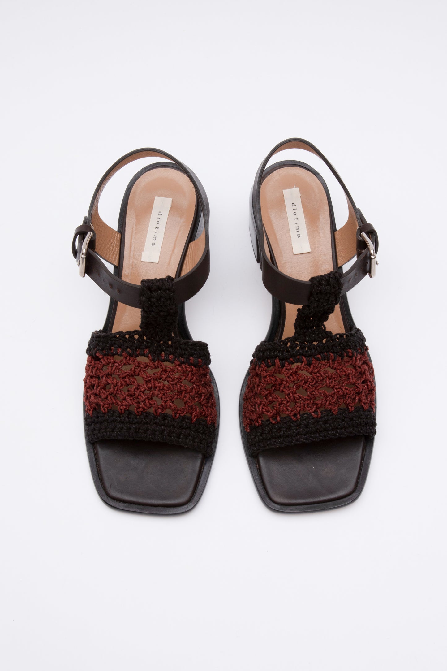 Open toe sandals with black leather base and ankle straps. The block heel is slightly rounded and thick. Connected to the ankle strap is a toe strap made from hand-knit crochet in black and maroon. 