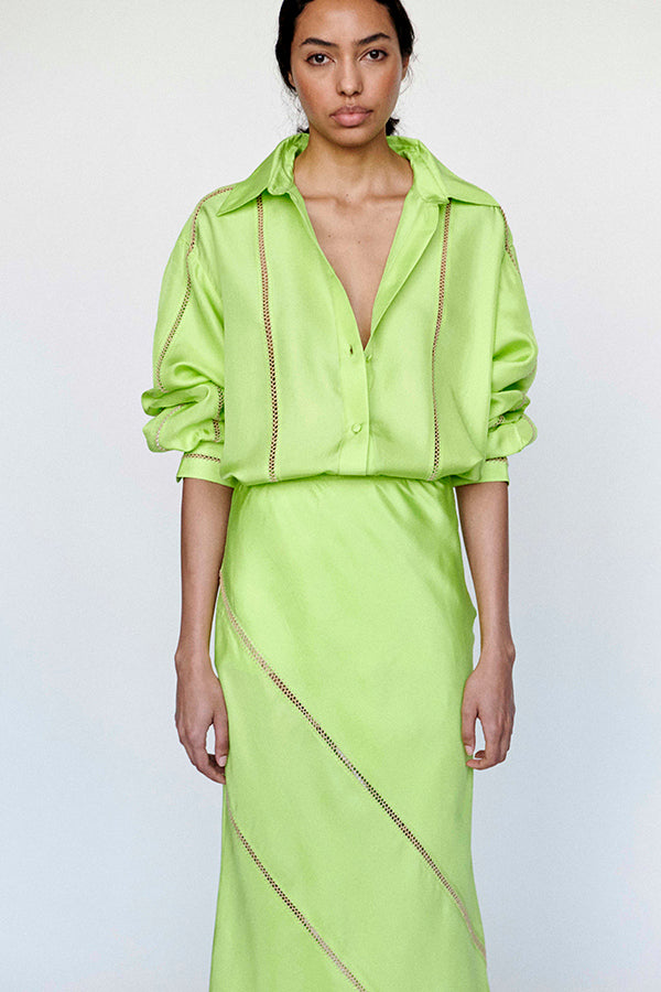 Woman wearing a bright green outfit with a matching top and skirt on a white background