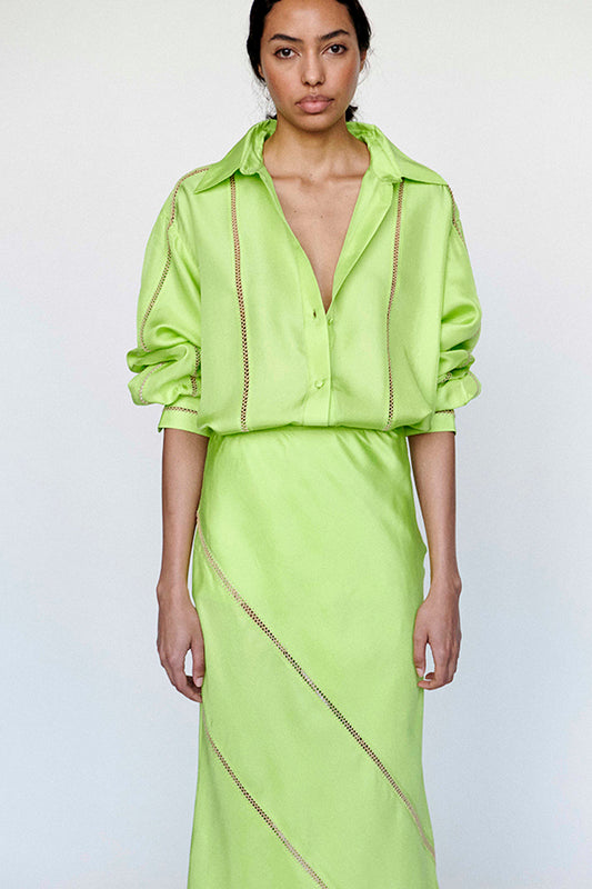 Woman wearing a bright green outfit with a matching top and skirt on a white background